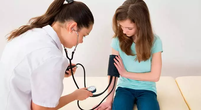 Подростку измеряет давление врач